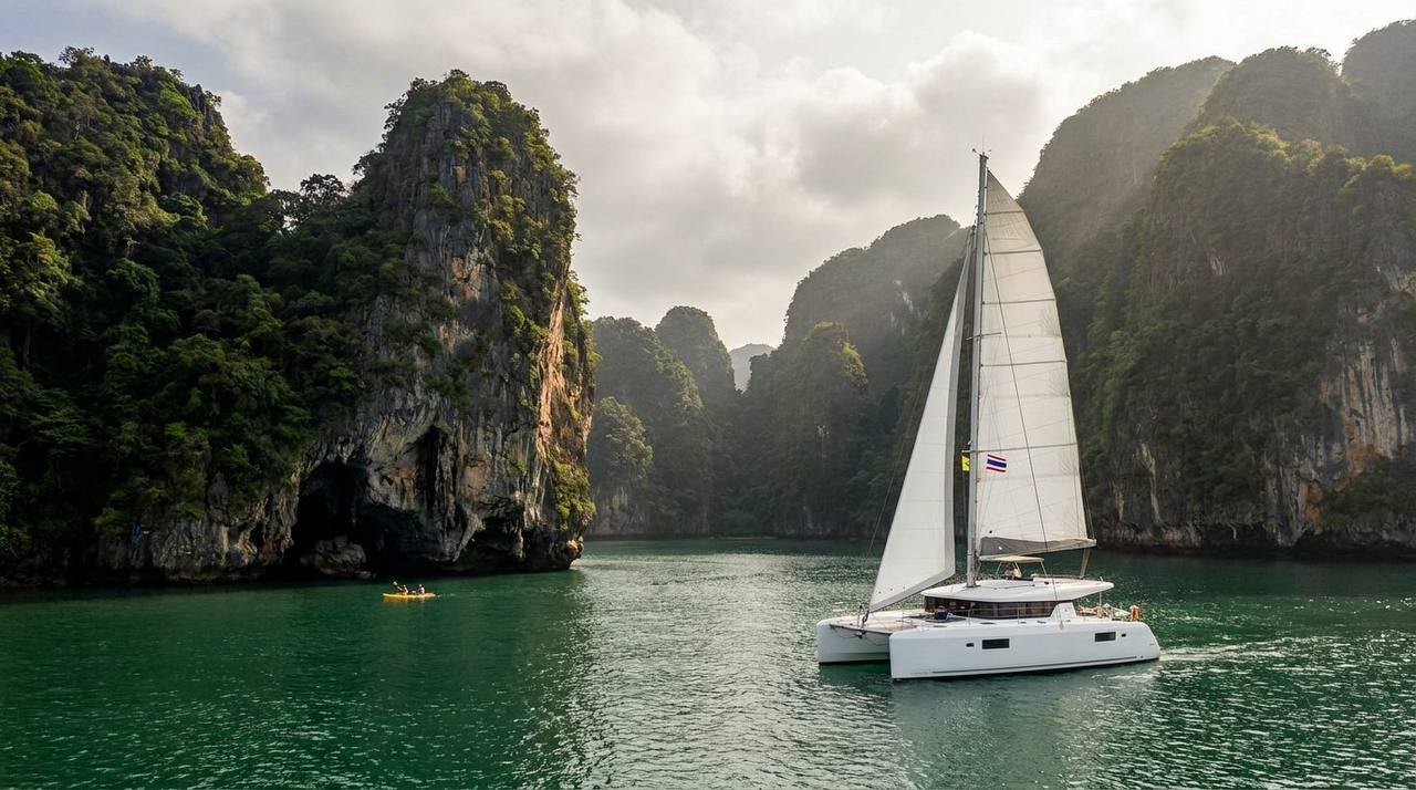 Sailing catamaran and kayak between the limestone cliffs of Phang Nga Bay